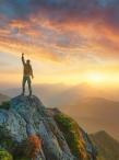 Man with arm upraised standing on mountain