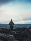 Woman watching rainbow over the sea