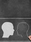 White and black heads or outlines drawn on a chalkboard