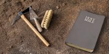 archaeological tools and a Bible laying on the dirt