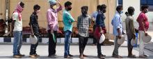 men wearing masks and waiting in line for food