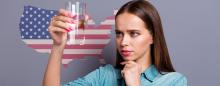 woman looking skeptically at a glass of water in front of a US map